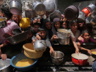 Palestinos tentam obter alimentos doados em uma cozinha comunitária em Jabalia, no norte da Faixa de Gaza