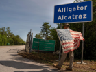 Imagem mostra um homem com a bandeira dos EUA na entrada da 'Alcatraz dos Jacarés', um centro de detenção de imigrantes da Flórida. Estado reivindica autonomia para deter migrantes sem status legal 