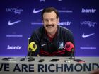 Jason Sudeikis em cena como Ted, técnico do time do Richmond, dando entrevista coletiva 