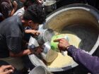 Palestinos deslocados tentam pegar o que resta em uma panela de sopa de lentilha em um ponto de distribuição de alimentos na cidade de Gaza, no norte da Faixa de Gaza, em 25 de julho de 2025. 