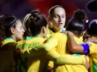 Jogadoras comemoram vitória com abraço em grupo no gramado.