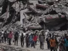 Palestinos em deslocamento carregando sacos de ajuda humanitária