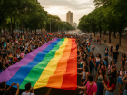 Multidão percorre as ruas de Campo Grande neste sábado (13) durante a 22ª Parada da Diversidade, com a tradicional bandeira arco-íris estendida pelos participantes.