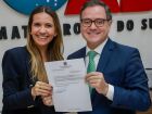 Caroline Karmouche Beal recebe das mãos do presidente da OAB/MS, Bitto Pereira, a nomeação para coordenar a comunicação da instituição.