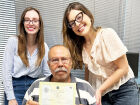 Ravadiel Ramão Sales recebe certidão de nascimento das mãos de Stephany Fonseca (à dir.), defensora, e Amanda Mehret, assessora jurídica