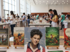 Ilustração de livros sobre São Carlo Acutis em destaque no estande da Paulinas Editora durante a 1ª Bienal do Livro do Pantanal, em Campo Grande.