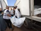 Funcionários do necrotério retiram os corpos de palestinos que estavam sob custódia israelense, após serem transportados em veículos da Cruz Vermelha.