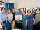 Luis Pedro Scalise apresenta a arte oficial da 5ª Feijoada Solidária ao lado das organizadoras do evento, em Campo Grande.