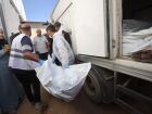 Funcionários do necrotério retiram os corpos de palestinos que estavam sob custódia israelense, após serem transportados em veículos da Cruz Vermelha. 