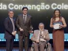 O presidente do Sistema Comércio MS, Edison Araújo, entrega troféu ao presidente do SEAC-MS, Eliziário Ferreira, acompanhado das representantes da entidade, durante premiação da categoria Relações Sindicais.