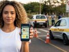 Jovem mostra no celular a CNH digital obtida com o novo aplicativo do governo, ao lado de carros de autoescola. O processo agora pode ser feito sem aula presencial.