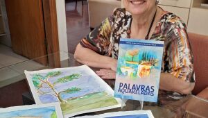 Maria Clara de Rezende Valle posa ao lado do livro Palavras aquareladas e das aquarelas pintadas por seu marido, Luiz Eduardo, que inspiraram os poemas da obra