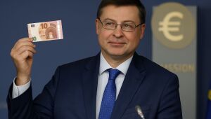 Valdis Dombrovskis, comissário de Economia da União Europeia, segura uma nota de euro durante coletiva em Bruxelas, no dia 8 de julho, data em que foi anunciada a entrada da Bulgária na zona do euro