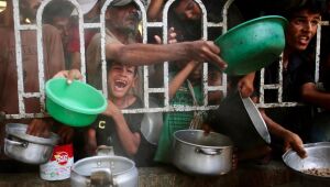 Palestinos tentam receber comida em uma zona humanitária na cidade de Khan Yunis, no sul da Faixa de Gaza