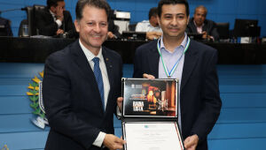 Deputado estadual Renato Câmara entrega a Comenda Antônio Tonani ao radialista e vereador Flavinho Lopes Lemes, durante sessão solene em homenagem ao Dia do Radialista, realizada pela Assembleia Legislativa de Mato Grosso do Sul