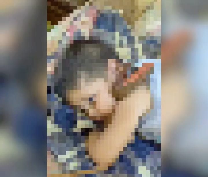 Menino de dois anos de idade deitado em um colchão e amarrado por uma coleira