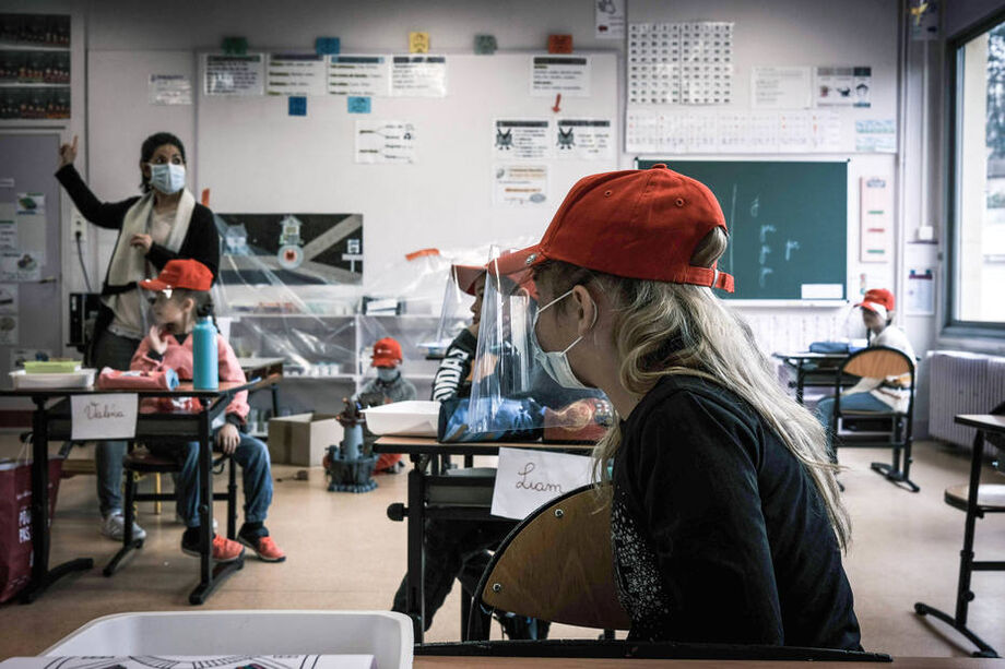 Alunos com equipamento de proteção em escola primária