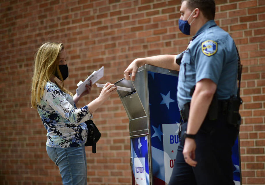 Eleitora deposita voto por correspondência em urna especial na cidade de Doylestown