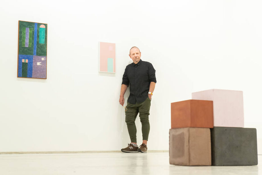 O pintor Paulo Pasta posa ao lado de sua tela