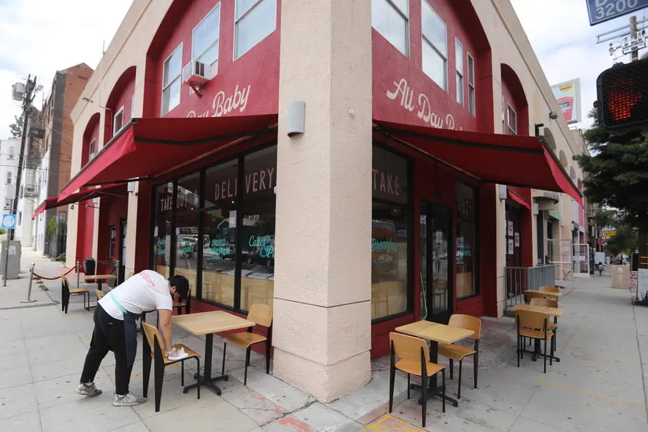 Funcionário de restaurante de Los Angeles, na Califórnia, higieniza assentos e mesas à espera de clientes