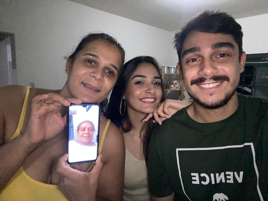 Matheus, junto à irmã e mãe, fala com a vó pelo celular