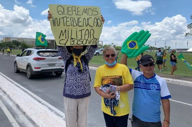 Manifestante mostra cartaz pedindo intervenção militar durante ato em Brasília