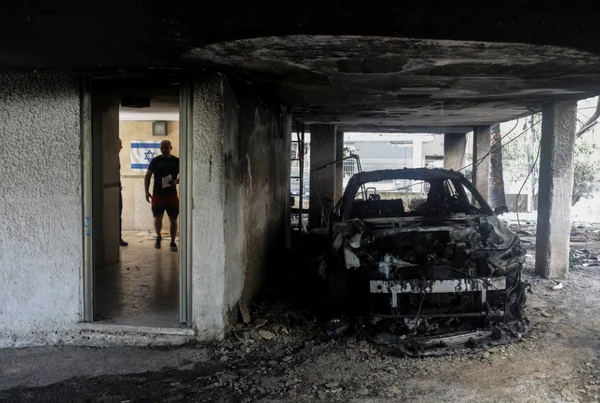 Homem ao lado de carro destruído em prédio atingido por foguete lançado de Gaza. Foto: REUTERS/Nir Elias