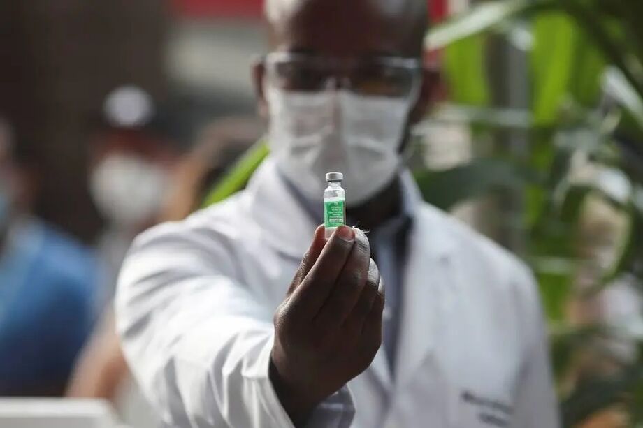 Servidor exibe frasco com vacina da AstraZeneca aplicada na sede da Fiocruz, no Rio de Janeiro