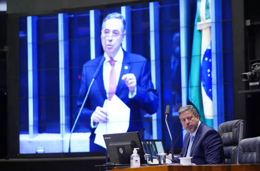 O presidente do TSE, Luís Roberto Barroso, no telão, e o residente da Câmara, Arthur Lira