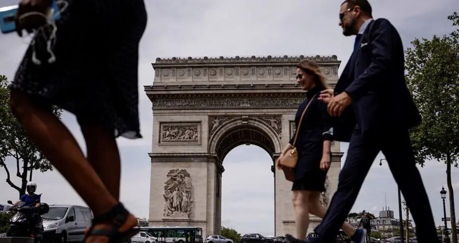 Pessoas sem máscara caminham em frente ao Arco do Triunfo, em Paris, depois que o governo francês retirou a obrigatoriedade da proteção contra o coronavírus em locais abertos.
