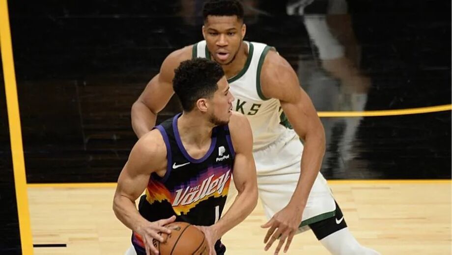 Devin Booker, dos Suns, com Giannis Antetokounmpo, dos Bucks, em jogo da temporada regular