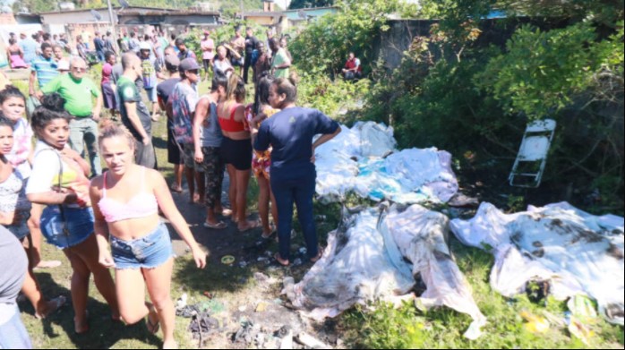 Moradores observam corpos retirados de área de mangue no Complexo do Salgueiro. Polícia realizou operação na região neste domingo