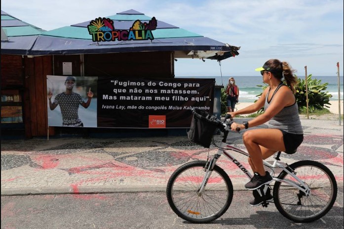 Mulher anda de bicicleta próximo ao quiosque Tropicália, onde Moïse foi assassinado, no Rio. Prefeitura oferece gestão do local à família do congolês