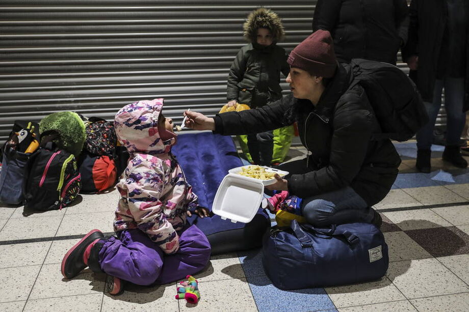 Uma mulher dá comida para seu filho no novo centro de refugiados.