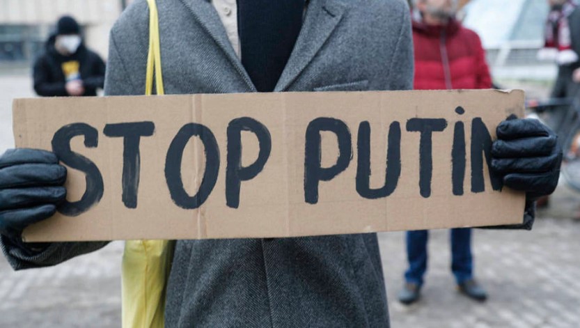Pessoa segura uma placa com a frase Pare, Putin, em Riga, na Letônia; invasão ocorre algumas horas depois de a Rússia afirmar ter recebido um pedido de ajuda dos separatistas pró-Rússia
