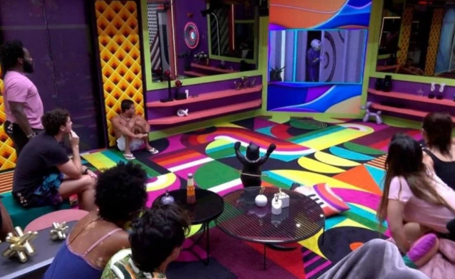 Integrantes do Big Brother Brasil 22 acompanham da sala da casa a movimentação do dummy no jardim
