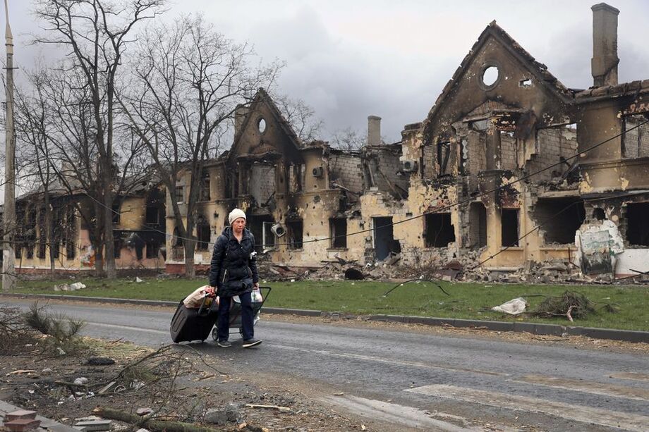 Ucraniana passa por casas destruídas por ataques russos em Mariupol.