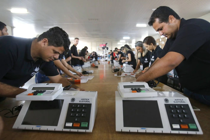 Servidores da Justiça Eleitoral preparam urnas eletrônicas.
