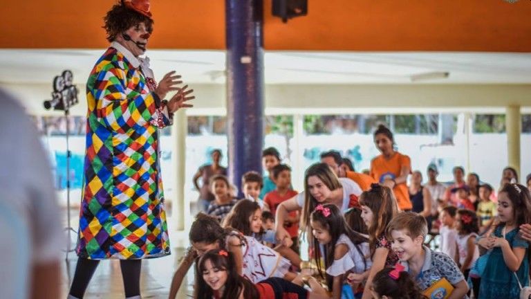 Artista e criança durante apresentação cultural em Campo Grande