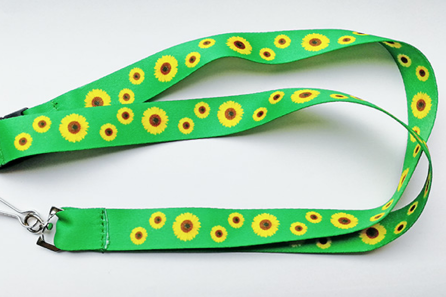 Considera-se o colar de girassol uma faixa estreita de tecido ou material equivalente, na cor verde, estampada com desenhos de girassóis