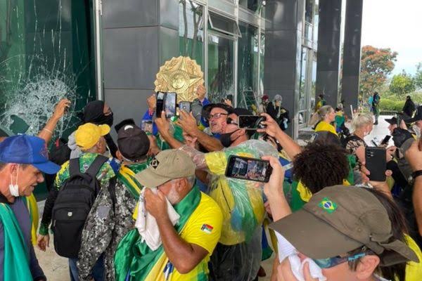 Manifestantes segurando o brasão do STF