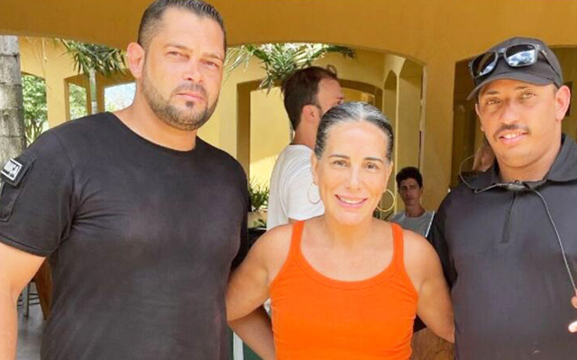 Glória Pires ao lado de seguranças