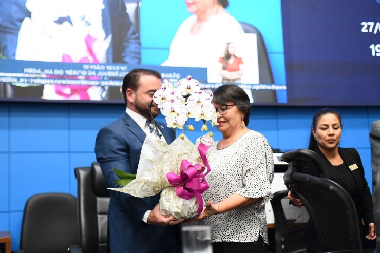 Deputado João César Mattogrosso entrega flores à senhora Roselene Ribeiro, mãe de Anderson Barão, durante sessão solene desta noite