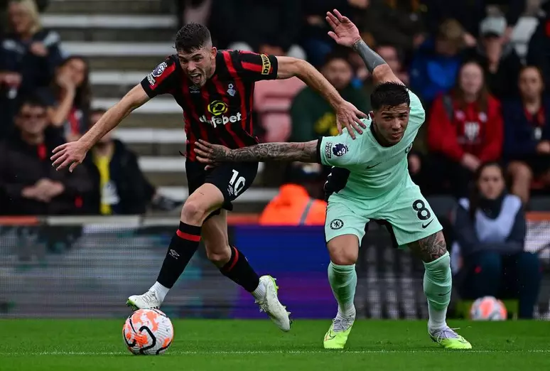 Ryan Christie, do Bournemouth (de rubro-negro, à esquerda) luta pela bola com Enzo Fernández, astro do Chelsea.