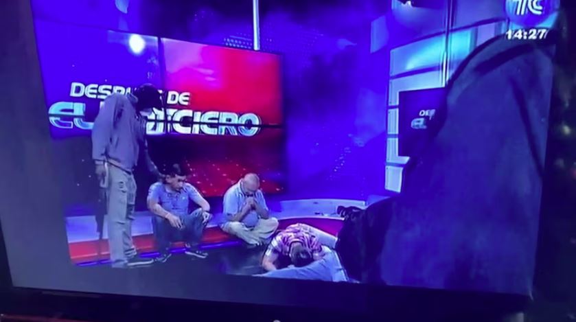 Profissionais de TV equatoriana no chão enquanto homens armados invadem estúdio durante transmissão ao vivo