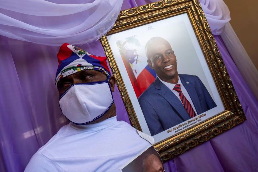 Um homem fica ao lado de um retrato do presidente haitiano Jovenel Moise, morto, colocado em um memorial na prefeitura de Cap-Haitien, Haiti, em 22 de julho de 2021