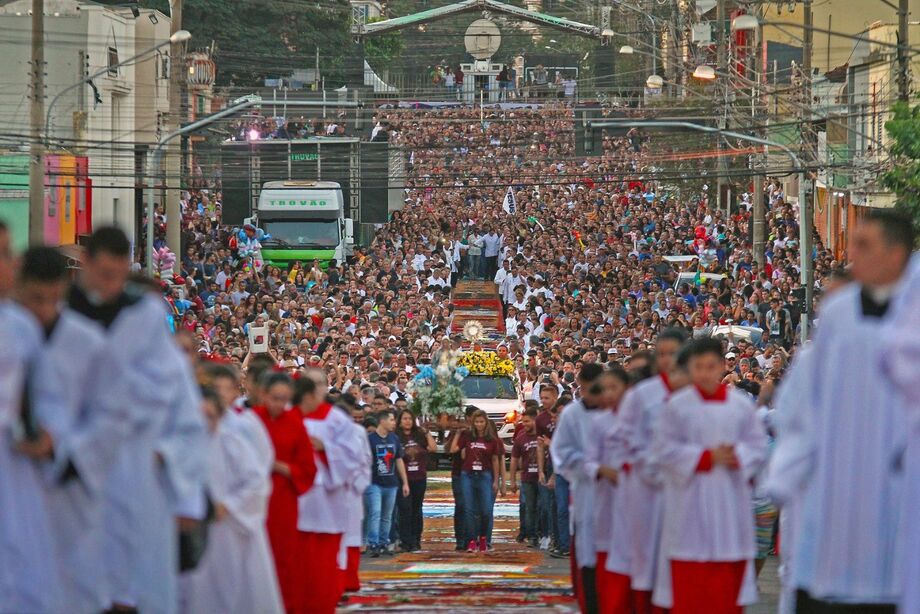 Fiéis participam da procissão de Corpus Christi em Campo Grande, destacando a fé e a tradição com tapetes de serragem colorida