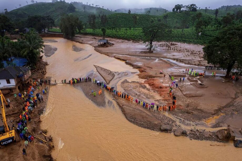 Socorristas atravessam rio por meio de ponte improvisada após deslizamentos de terra na Índia