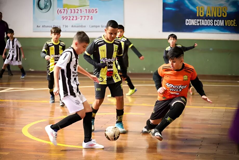 Jovens jogadores disputam a bola em partida de futsal da Copa Pelezinho.