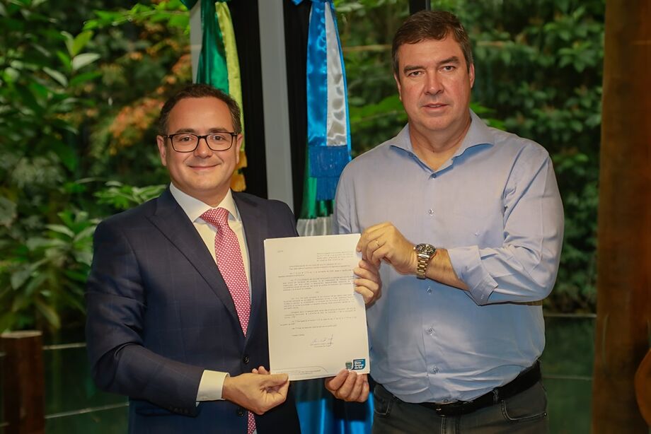 O governador Eduardo Riedel (à direita) segurando o documento de sanção da nova lei ao lado de Bitto Pereira (à esquerda), presidente da OAB-MS.